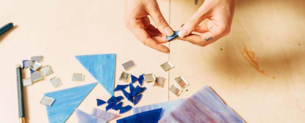 des mains qui font un travail de mosaïques