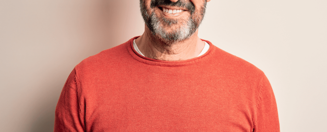 homme souriant avec une barbe et un pull orange 