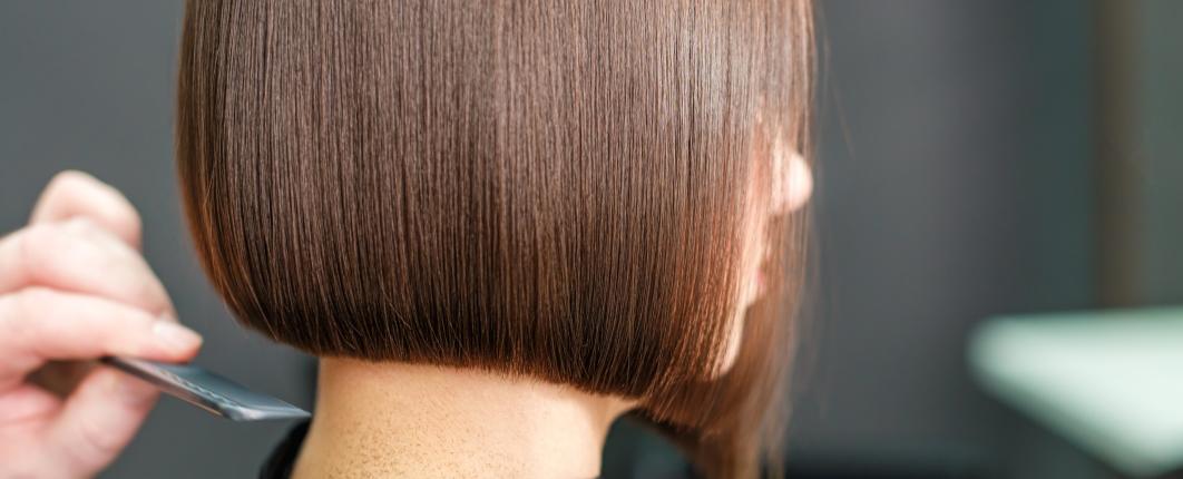 Femme brune avec un carré en train de se faire coupé les cheveux 