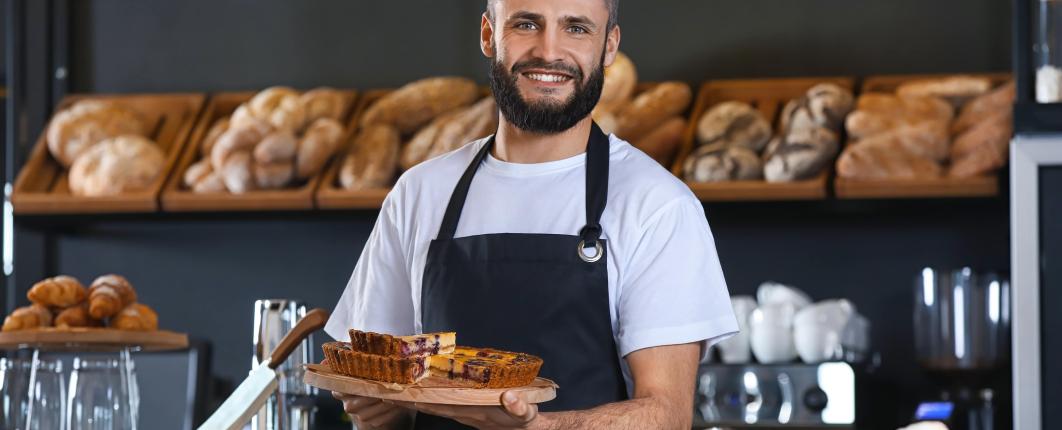 Un homme dans une boulangerie entouré de pain tient une tarte