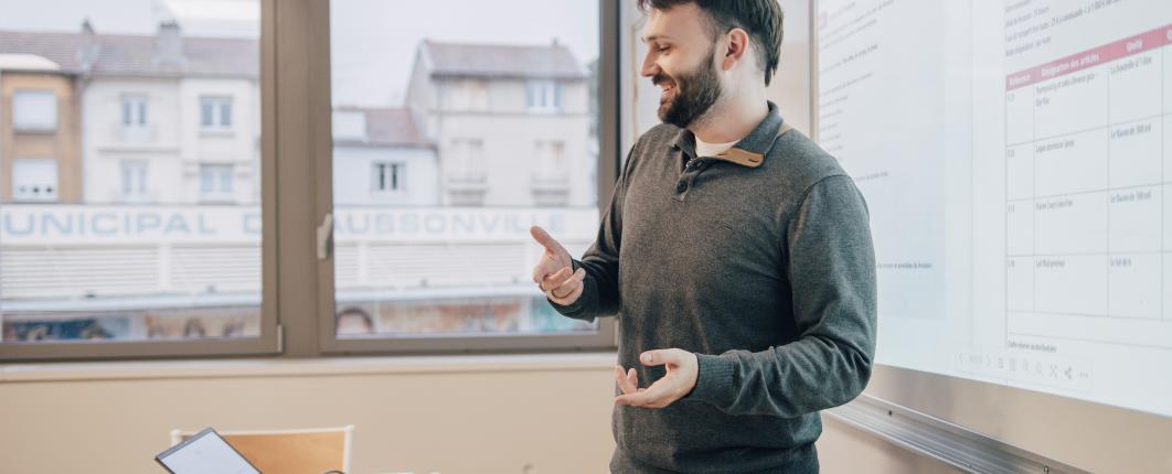 un professeur est devant un tableau et donne un cours