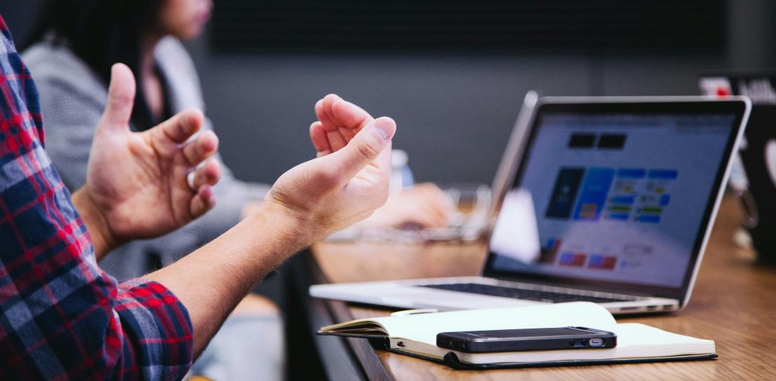 Homme qui parle avec son ordinateur ouvert devant lui