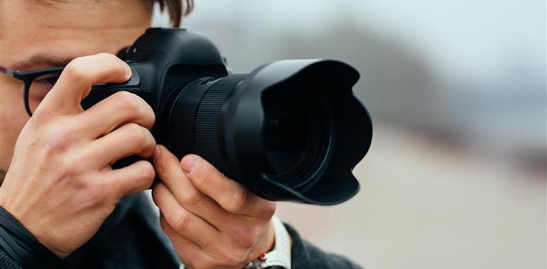 Vue de détail du jeune homme à lunettes prenant des photos dans la rue.