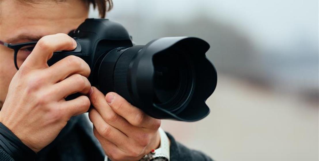 Vue de détail du jeune homme à lunettes prenant des photos dans la rue.