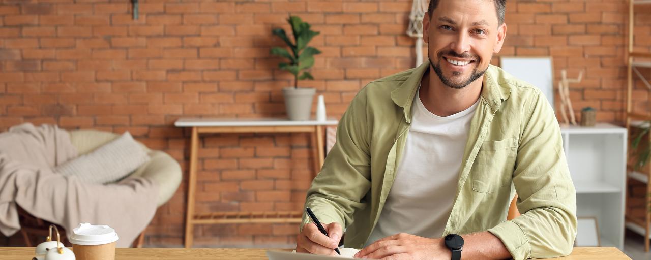 une personne sourit assis à une table avec un ordinateur