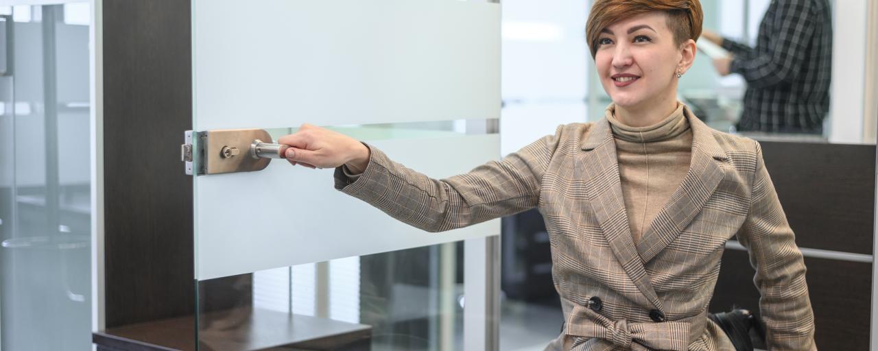 personne en fauteuil qui ouvre une porte 