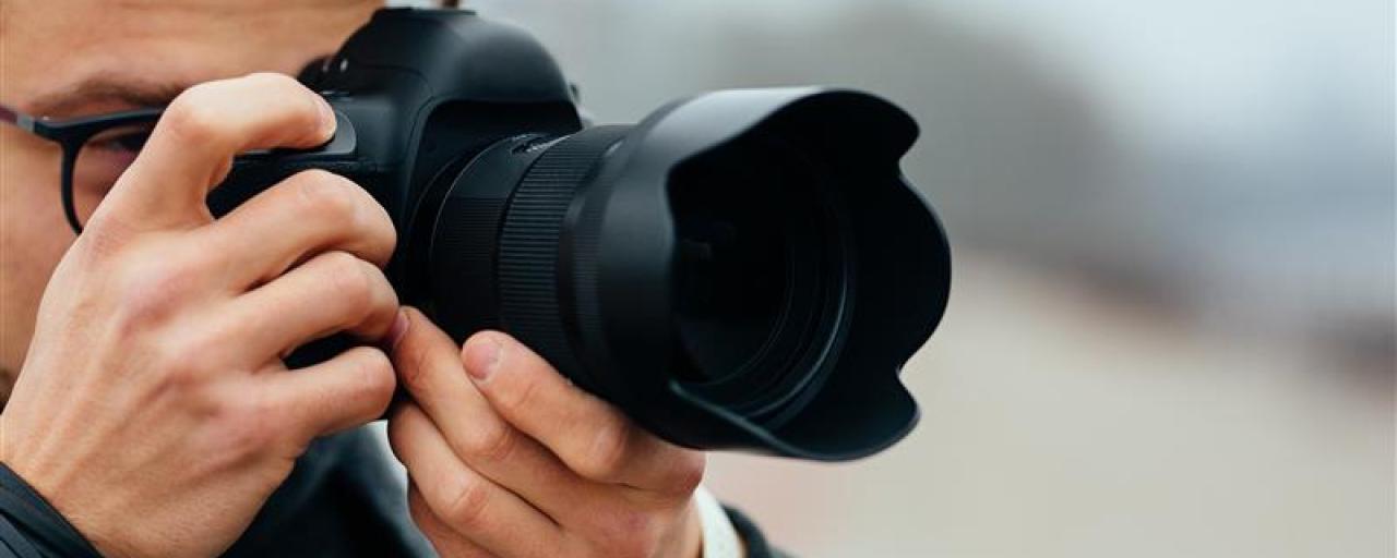 Vue de détail du jeune homme à lunettes prenant des photos dans la rue.