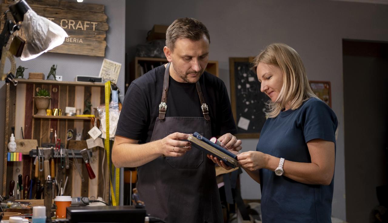 un homme et une femme regardent un carnet dans un atelier 