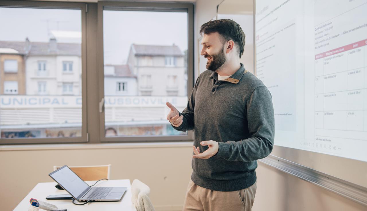 un professeur est devant un tableau et donne un cours