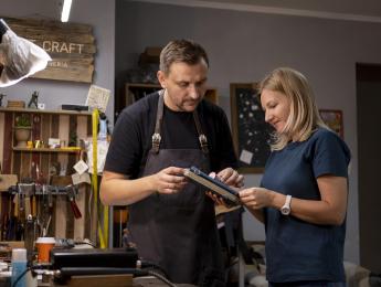 un homme et une femme regardent un carnet dans un atelier 
