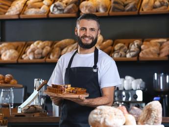 Un homme dans une boulangerie entouré de pain tient une tarte 