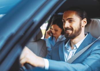 image d'un homme chauffeur VTC qui conduit une femme au téléphone