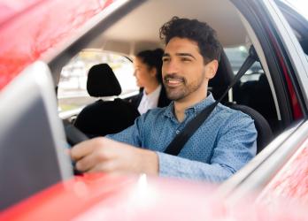 chauffeur de taxi au volant avec une cliente à l'arrière 