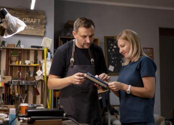 un homme et une femme regardent un carnet dans un atelier 