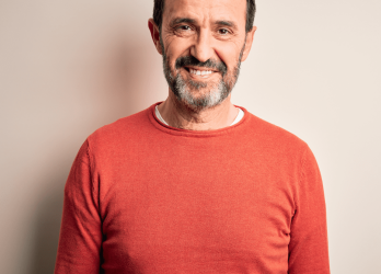 homme souriant avec une barbe et un pull orange 