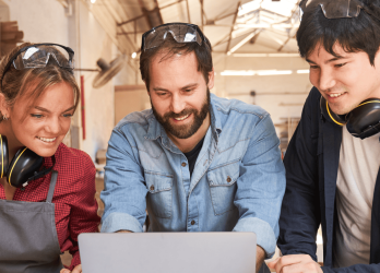 3 personnes souriantes devant un ordinateur