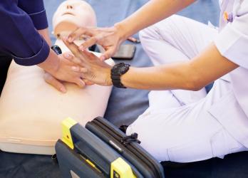 Personne en train de simuler un massage cardiaque sur un mannequin