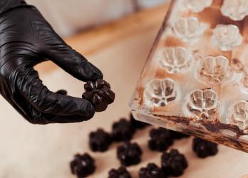 Main avec un gant qui retire un chocolat d'un moule