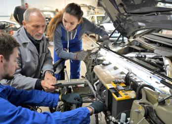 Plusieurs mécaniciens qui œuvrent dans un capot de voiture ouvert 