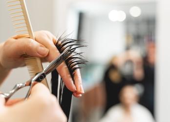 Focus sur une personne en train de couper une mèche de cheveux dans un salon de coiffure 