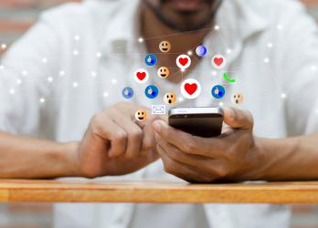 Homme qui scroll sur son smartphone et qui récolte de nombreuses réactions Facebook : Like, smiley... 