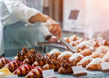 Boulanger qui attrape un croissant au chocolat avec une pince dans sa vitrine