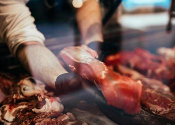 Homme tenant un morceau de viande dans une vitrine 