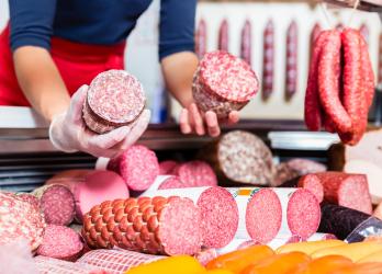 une dame tient en main des jambon et salami