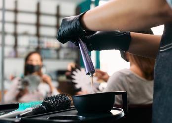 un coiffeur fait couler de la couleur dans un pot