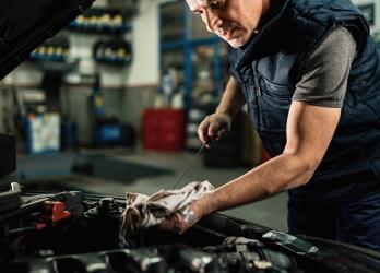 mecanicien-automobile-verifiant-l-huile-dans-le-moteur-de-la-voiture-tout-en-travaillant-dans-un-atelier-de-reparation-automobile