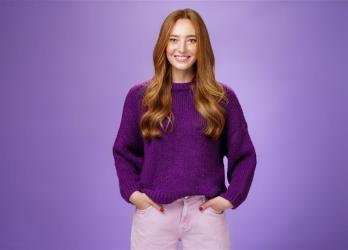 Femme qui sourit et croise les bras habillé en violet