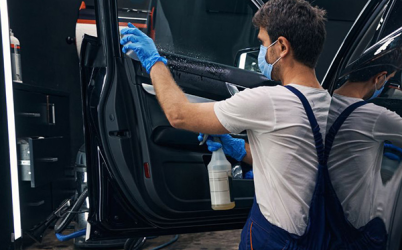 Un homme utilise un produit d'entretien sur l'intérieur d'une portière de voiture