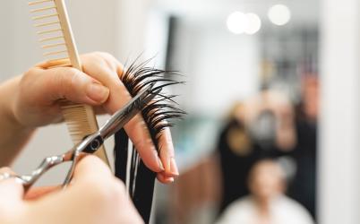 Focus sur une personne en train de couper une mèche de cheveux dans un salon de coiffure 