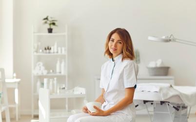 Femme esthéticienne qui se tient en souriant dans son institut 