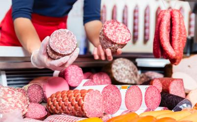 une dame tient en main des jambon et salami