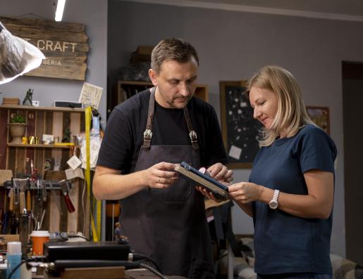 un homme et une femme regardent un carnet dans un atelier 