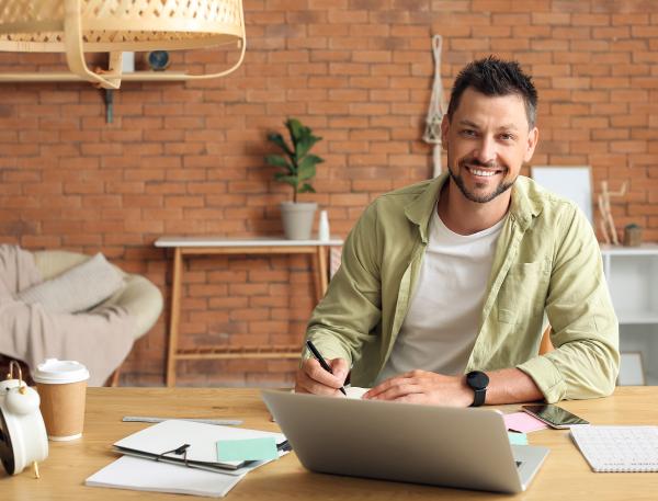 une personne sourit assis à une table avec un ordinateur