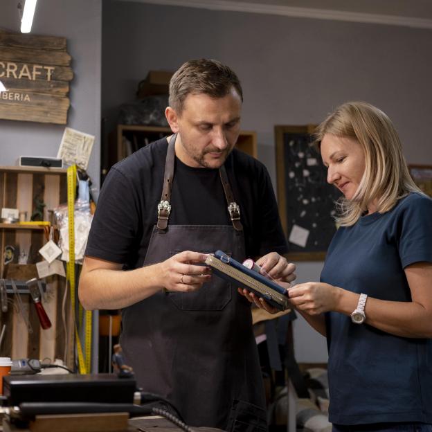 un homme et une femme regardent un carnet dans un atelier 