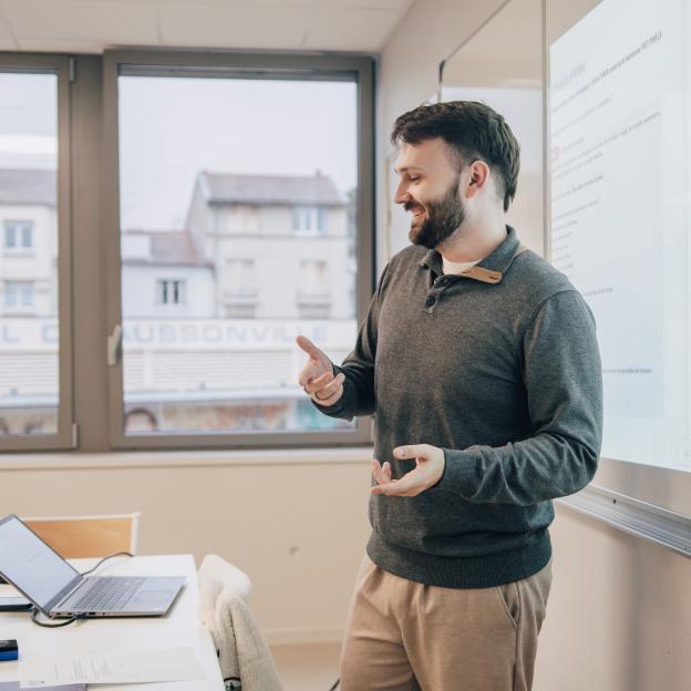 un professeur est devant un tableau et donne un cours