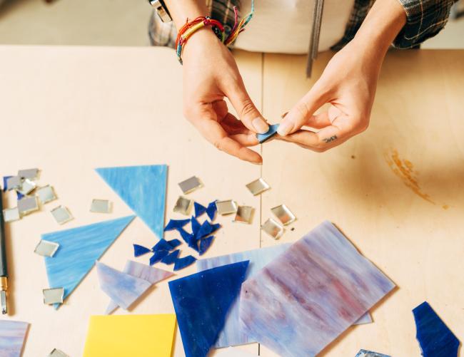 des mains qui font un travail de mosaïques 