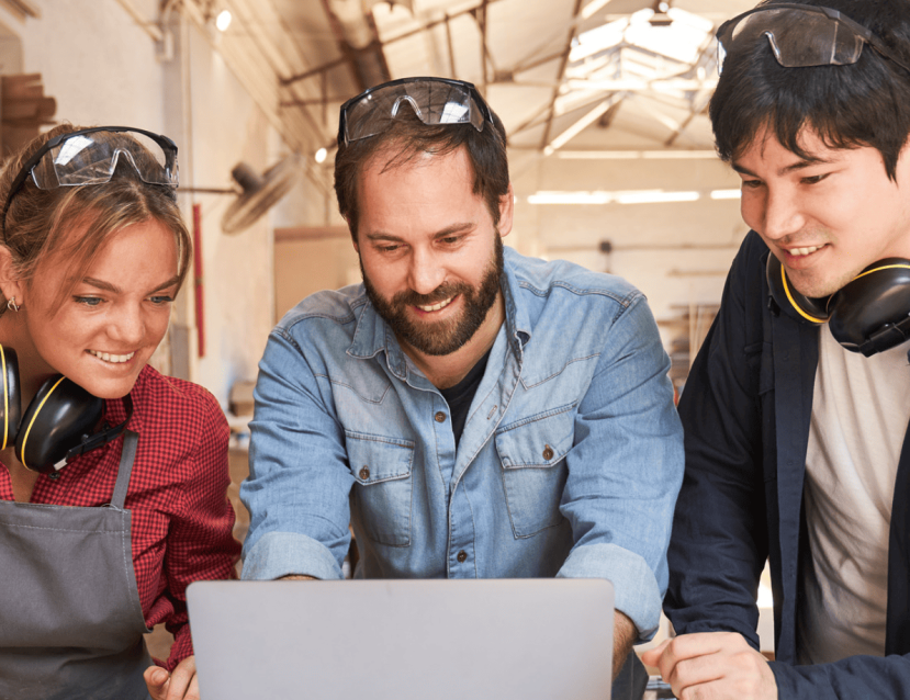 3 personnes souriantes devant un ordinateur