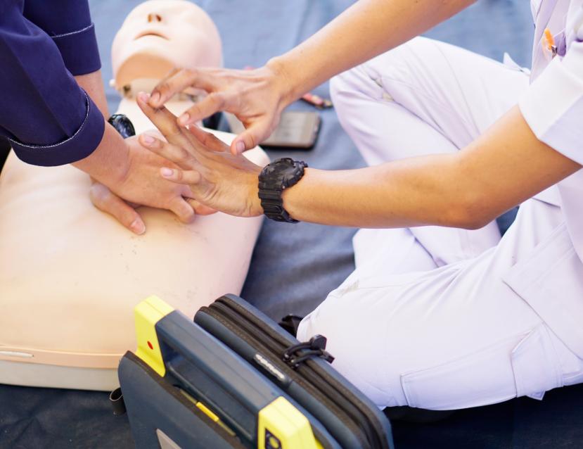 Personne en train de simuler un massage cardiaque sur un mannequin
