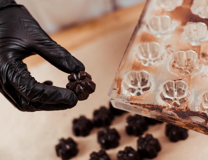 Main avec un gant qui retire un chocolat d'un moule