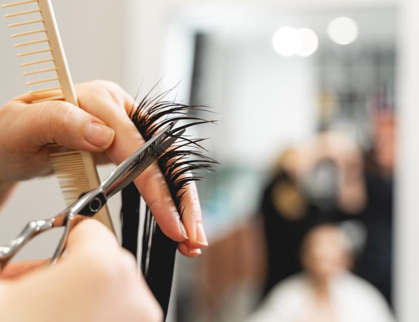 Focus sur une personne en train de couper une mèche de cheveux dans un salon de coiffure