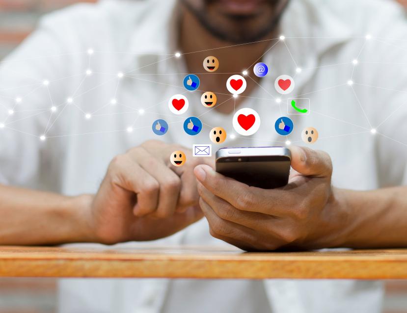 Homme qui scroll sur son smartphone et qui récolte de nombreuses réactions Facebook : Like, smiley... 