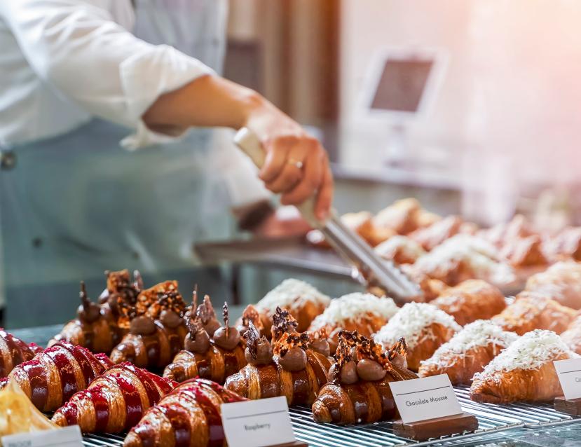 Boulanger qui attrape un croissant au chocolat avec une pince dans sa vitrine
