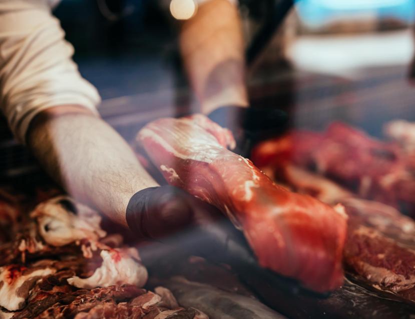 Homme tenant un morceau de viande dans une vitrine