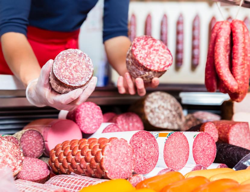 une dame tient en main des jambon et salami
