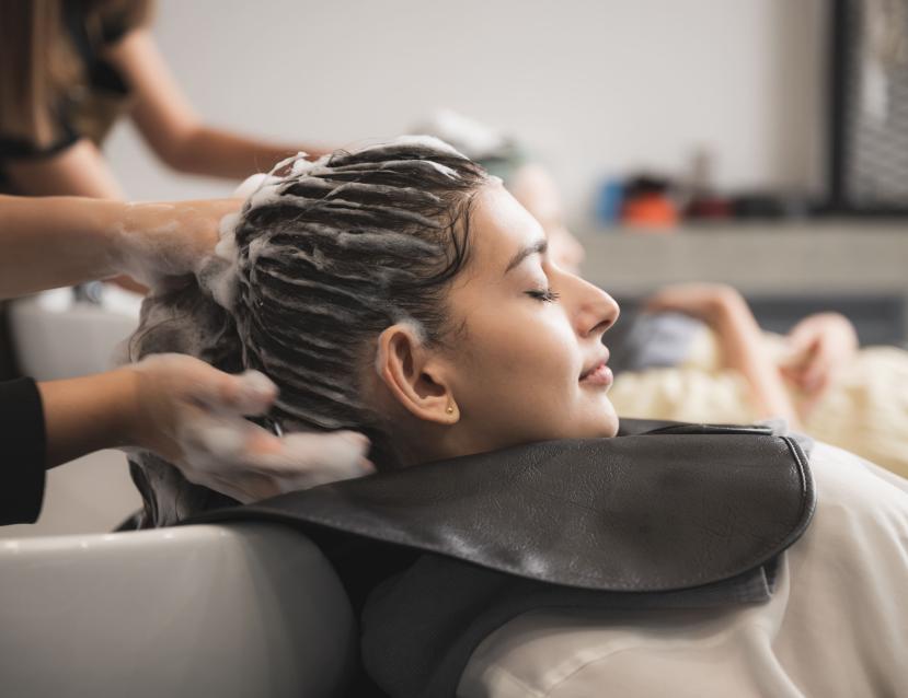 une coiffeuse fait un shampoing à une cliente