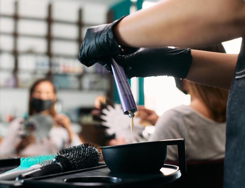 un coiffeur fait couler de la couleur dans un pot
